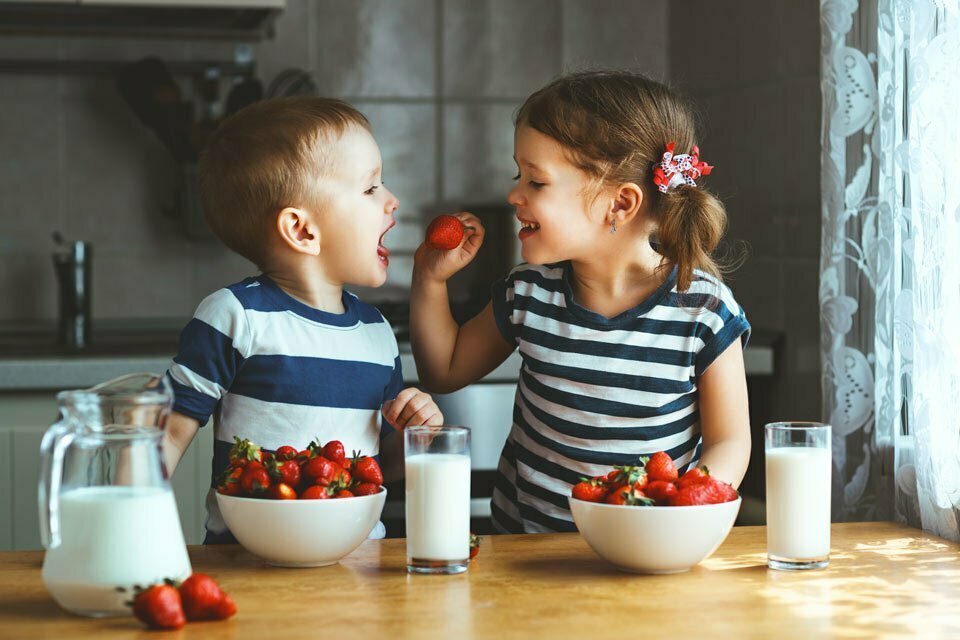 young children feeding each other strawberries