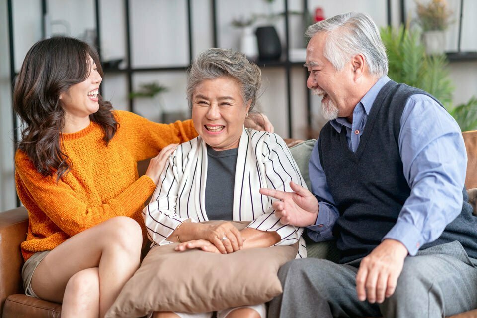 girl with grandparents laughing together on the couch