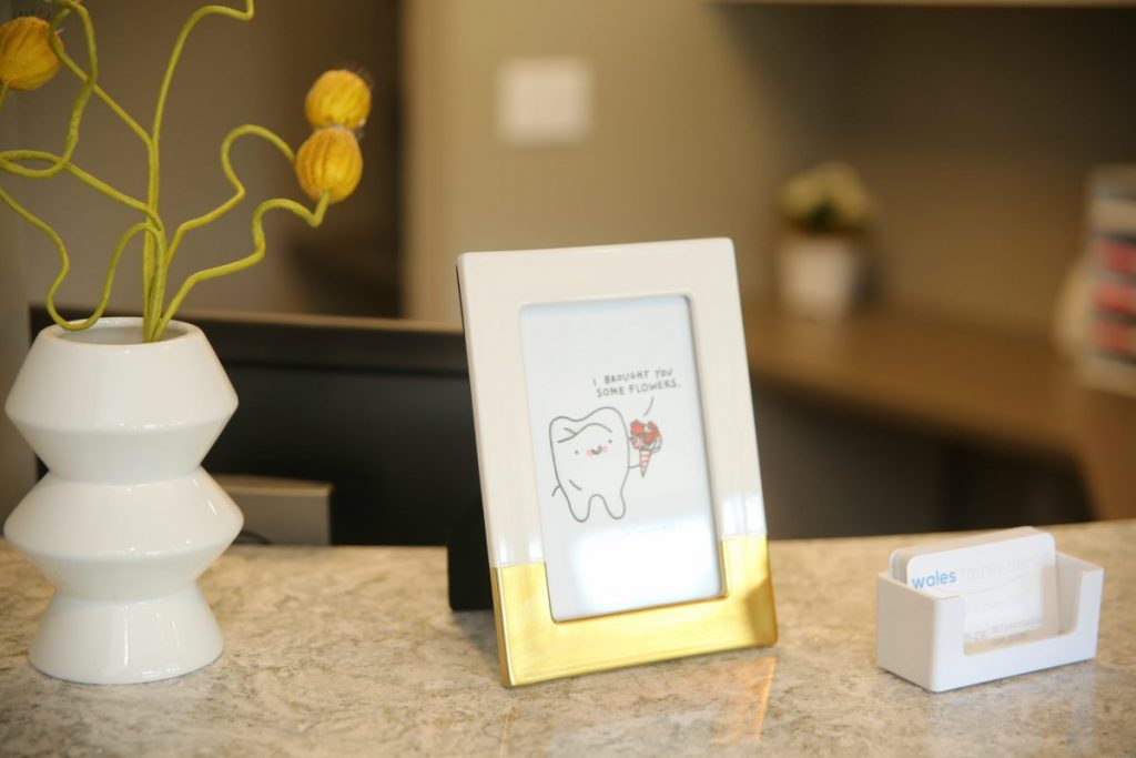 framed photo of a hand drawn tooth holding flowers, inside an office