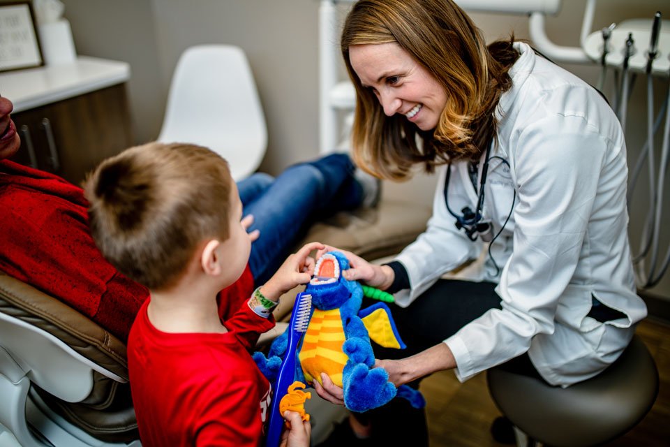 dentist giving child a dinosaur dentist toy to play with