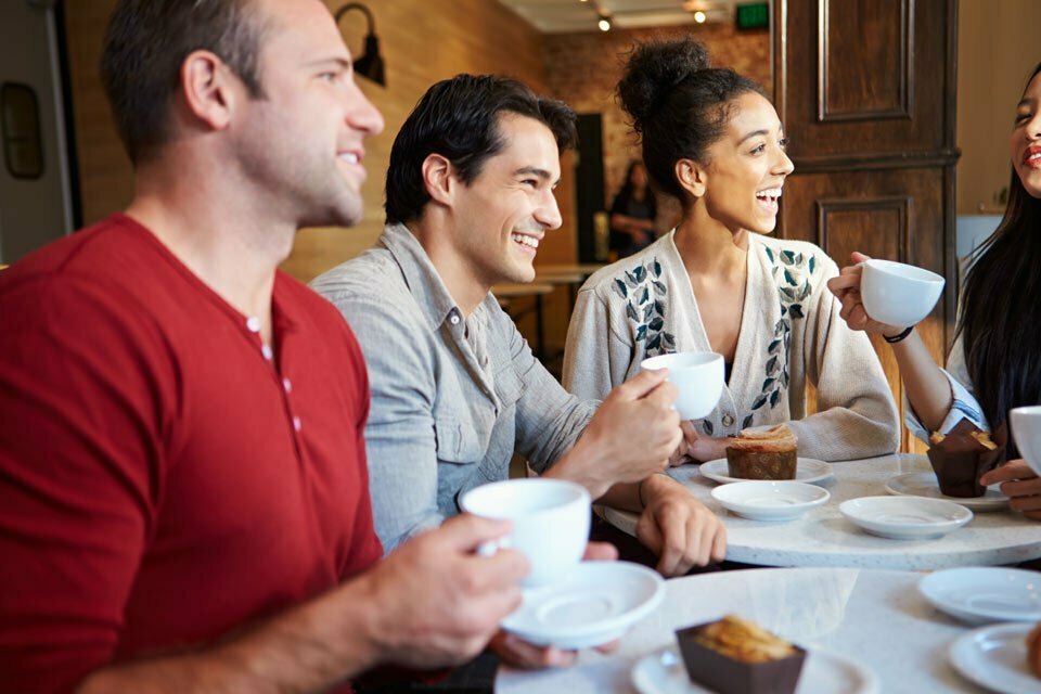 group of people laughing while drinking coffee